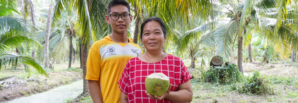 man and woman holding fresh coconuts in front of palm trees